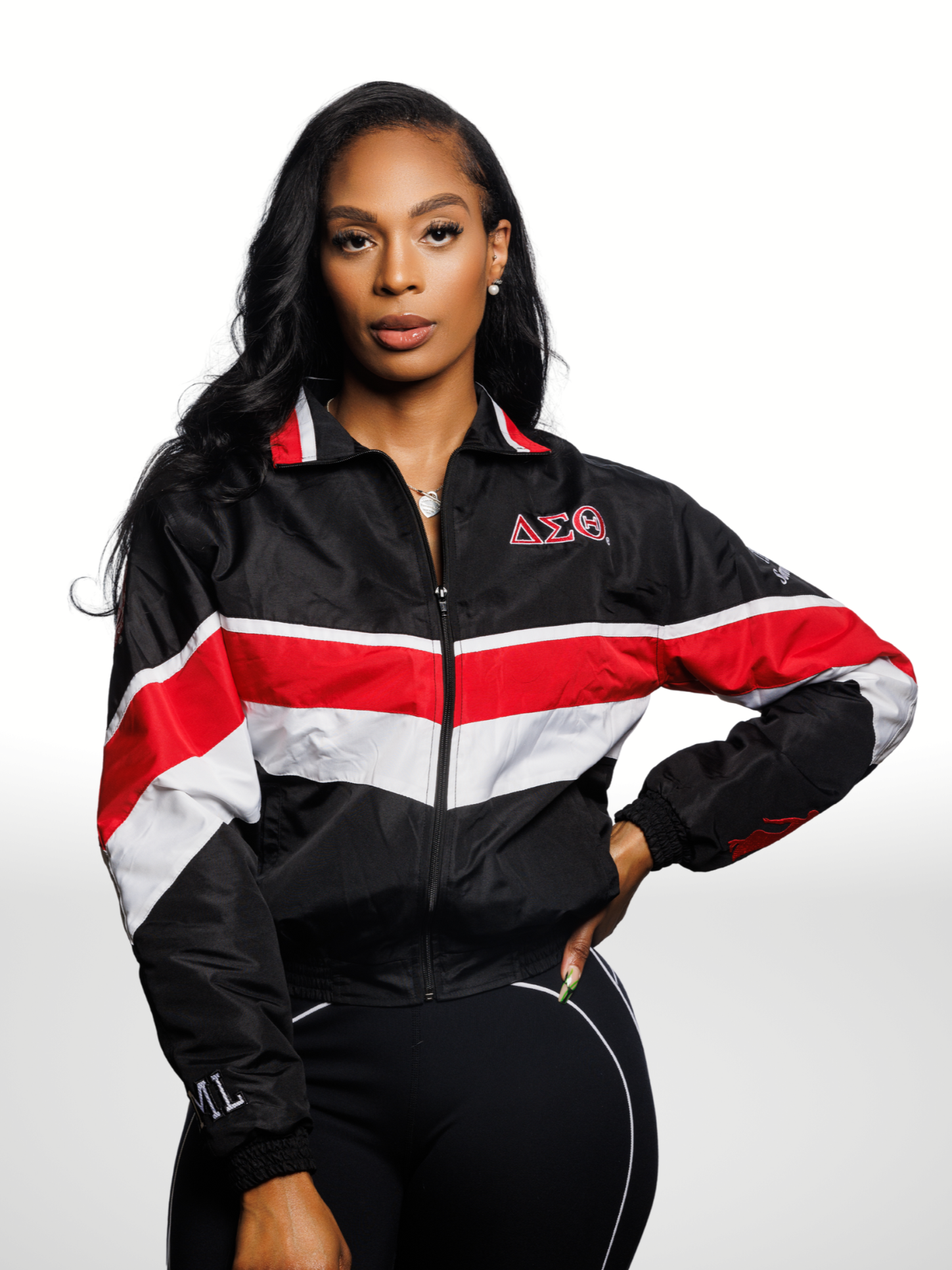 Person wearing a black, red, and white jacket with a logo on a gray background